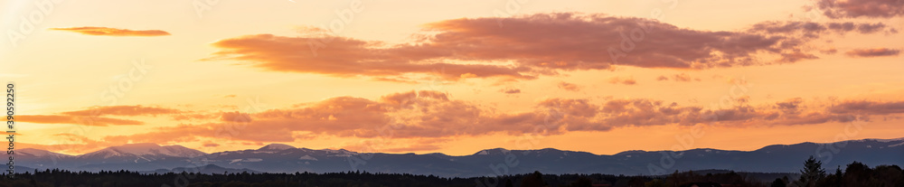 Styrian Lavanttaler Alps covered with snow in orange light of sunset. Background or banner