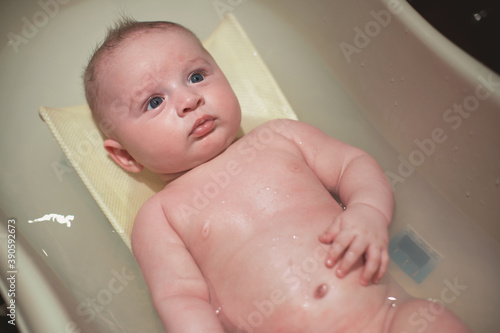 Infant baby boy washed in small bath tub, view from above