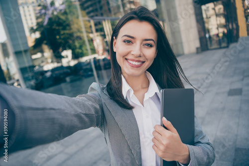 Photo of attractive positive young businesswoman take selfie hold laptop outdoors in downtown city center