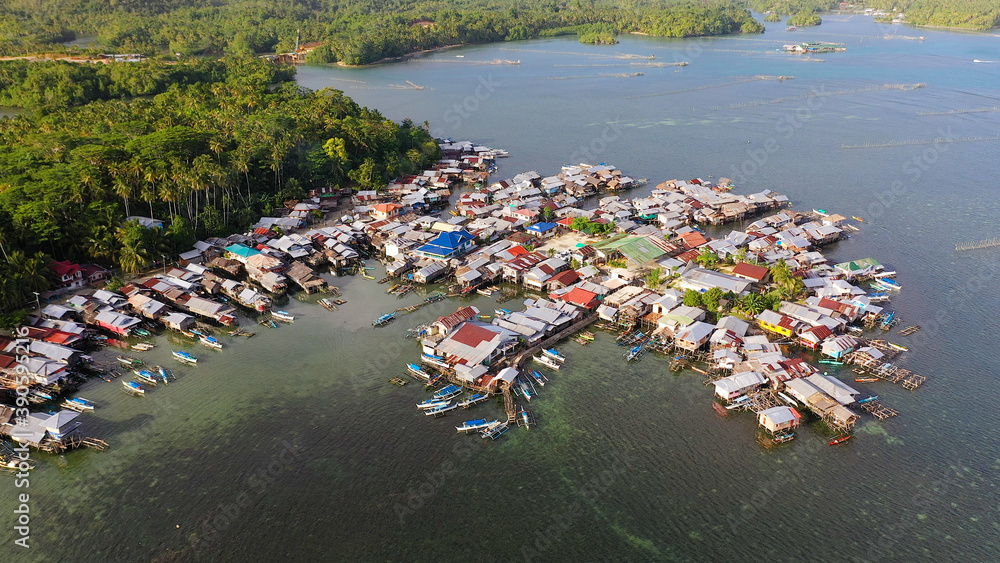 Village of fishermen with houses on the water, with fishing boats. Fishing village with wooden houses on stilts in the sea. Philippines, Mindanao.