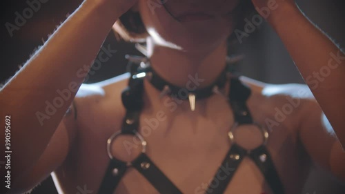 Sexy woman in a leather bondage puts on a studded collar photo