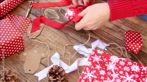 Woman ties a ribbon bow and wrapping presents