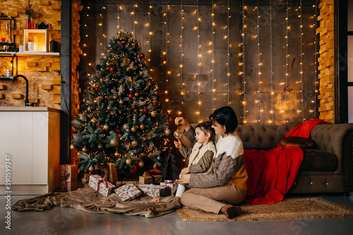 Mother and daughter decorating christmas tree at home.