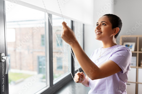 people and leisure concept - happy young african american woman opening window roller blinds at home Free Download people and leisure concept - happy young african american woman opening window roller blinds at home - GFXLoad