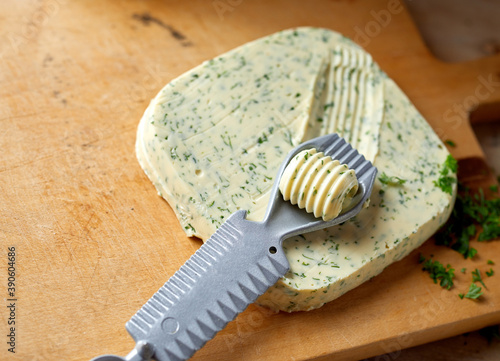 Butter curler cutting a pat of herb butter photo