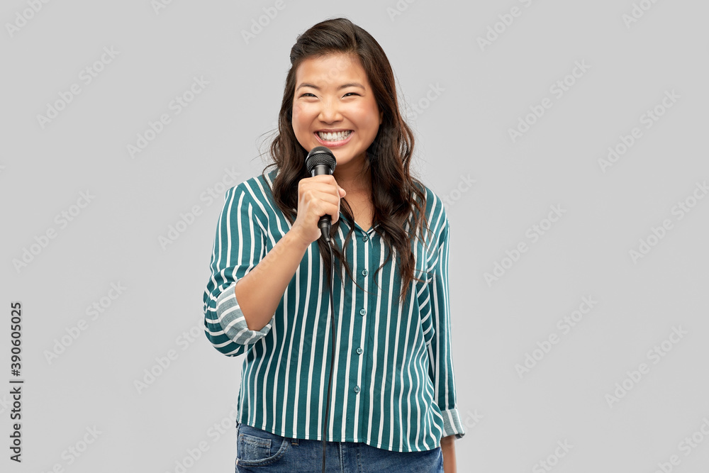 people, ethnicity and portrait concept - happy smiling asian young woman with microphone singing over grey background people, ethnicity and portrait concept - happy smiling asian young woman with microphone singing over grey background