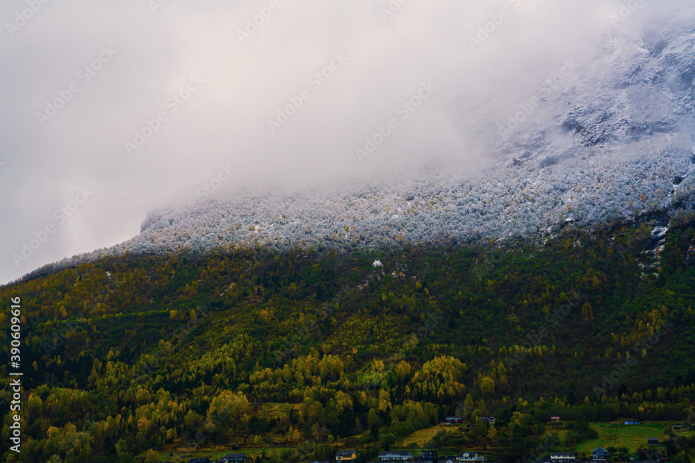 Mountain ridge with a clear snow line covered in dense stormy clouds.