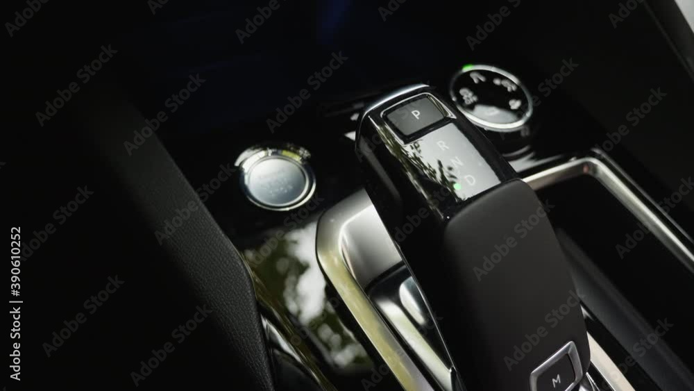 Close-up of the male driver hand switches the automatic transmission lever from P (parking) to D (drive) Close-up of the male driver hand switches the automatic transmission lever from P (parking) to D (drive)