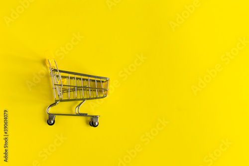 Empty shopping grocery cart on yellow background. Concept of business, shopping, black friday sales. Top view or flat lay composition