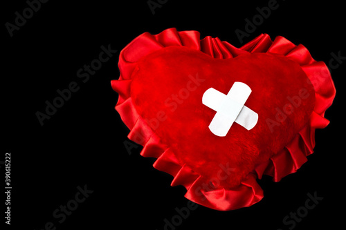 Photos Red wounded broken heart taped by medical plaster crosswise on black background