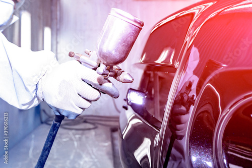 Technician's hand In standard safety clothing The car is spraying paint