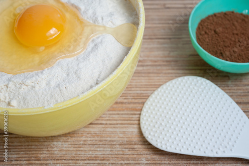 egg hammered in a bowl of flour, next to a bowl of cocoa