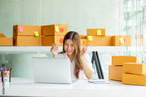 Starting Small business entrepreneur SME freelance,Portrait young woman working at home office, BOX,smartphone,laptop, online, marketing, packaging, delivery, SME, e-commerce concept   © David