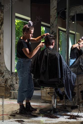 shot of hairdresser cutting hair of handsome hipster client, Hairstylist serving client at barber shop