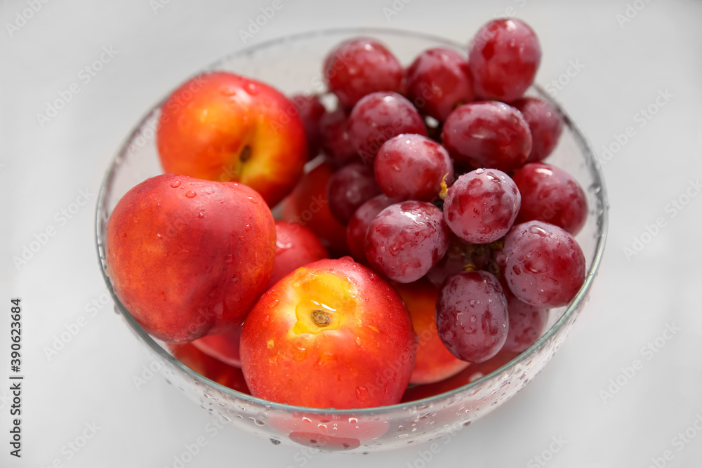Glass bowl with fresh grapes and nectarines on white table, closeup Glass bowl with fresh grapes and nectarines on white table, closeup