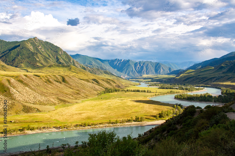 A picturesque valley with a winding river among the mountains against the backdrop of a beautiful sky