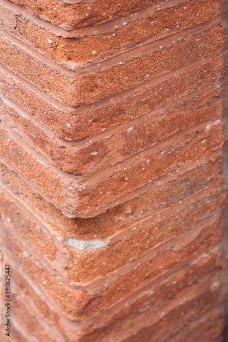 Close up of a corner of a brown brick wall. Materials. Cracks on the brick wall.