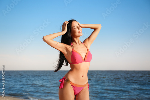 Beautiful young woman in pink stylish bikini on beach