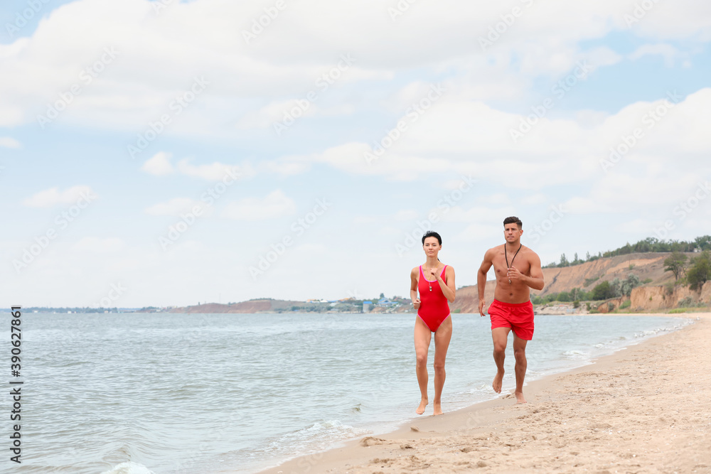 Professional lifeguards running at sandy beach on sunny day