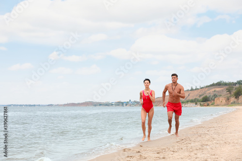 Professional lifeguards running at sandy beach on sunny day