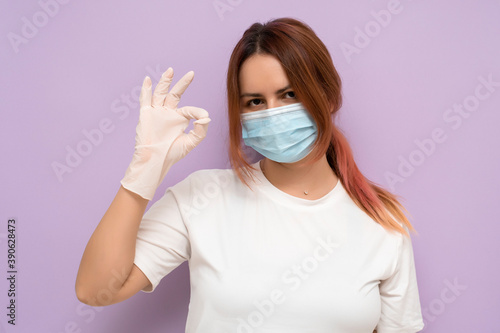 woman in a respirator mask on a lilac background in latex gloves