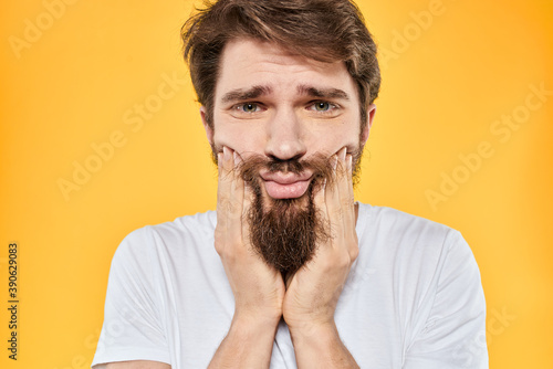 A man in a white t-shirt gestures with his hands studio lifestyle yellow background emotions © SHOTPRIME STUDIO