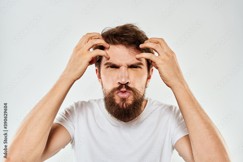 Emotional bearded man in a white t-shirt gestures with his hands light background Emotional bearded man in a white t-shirt gestures with his hands light background