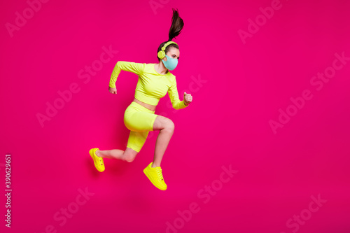 Full length body size side profile photo of sportswoman jumping high running fast wearing mask isolated on vivid fuchsia color background