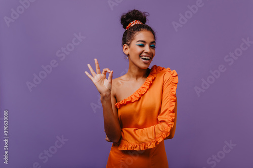 Romantic african girl having fun in studio. Cute dark-haired lady standing on violet background.