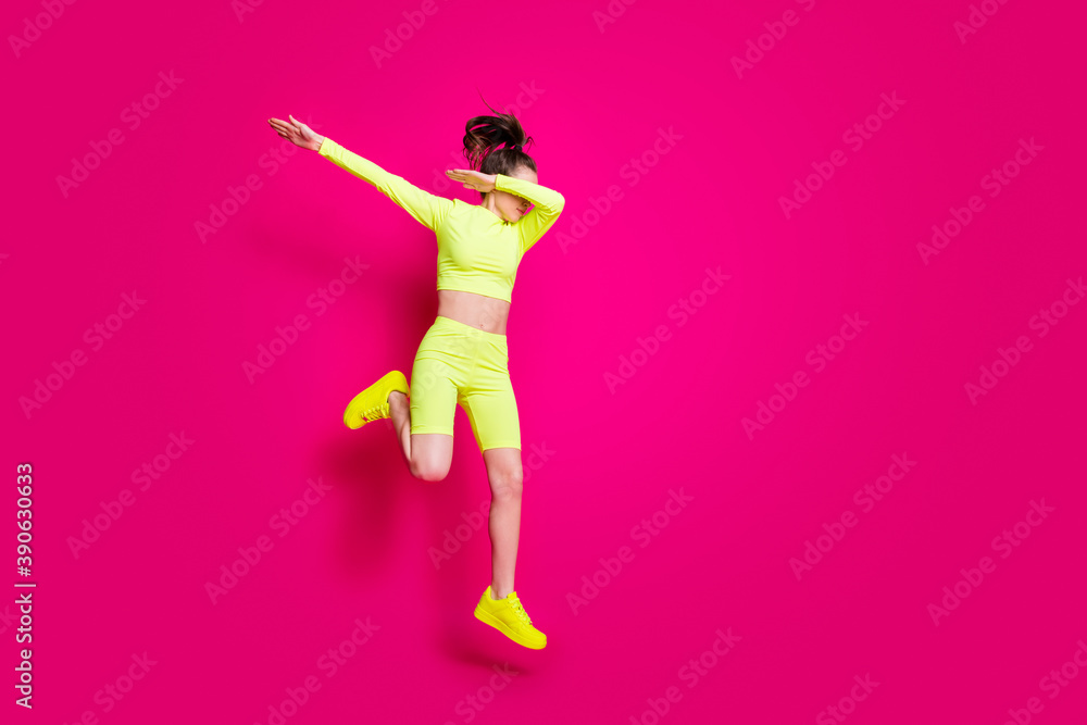 Full length body size photo of jumping sportswoman wearing yellow sportswear sneakers showing hype isolated on vivid pink color background Full length body size photo of jumping sportswoman wearing yellow sportswear sneakers showing hype isolated on vivid pink color background