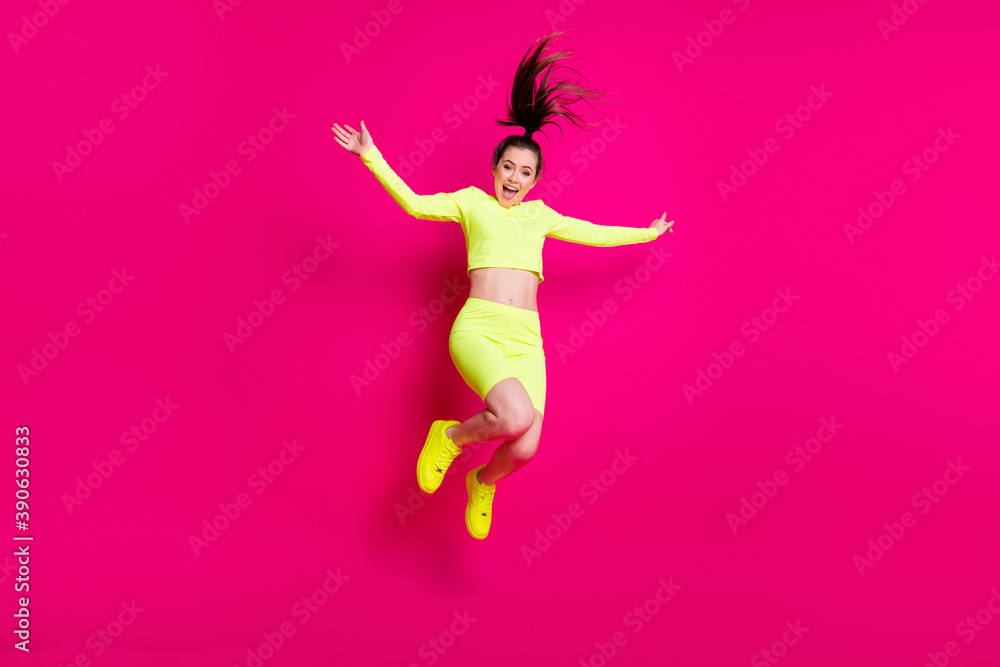 Full length body size photo of jumping high shouting energetic sporty girl laughing isolated on vibrant pink color background Full length body size photo of jumping high shouting energetic sporty girl laughing isolated on vibrant pink color background