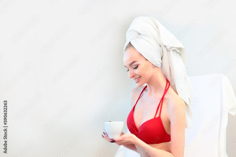 The woman tied a white terry towel around her head. Wellness concept. Spa. Copy space. Photo on a white background. A white cup with tea in a woman's hand. The woman tied a white terry towel around her head. Wellness concept. Spa. Copy space. Photo on a white background. A white cup with tea in a woman's hand.