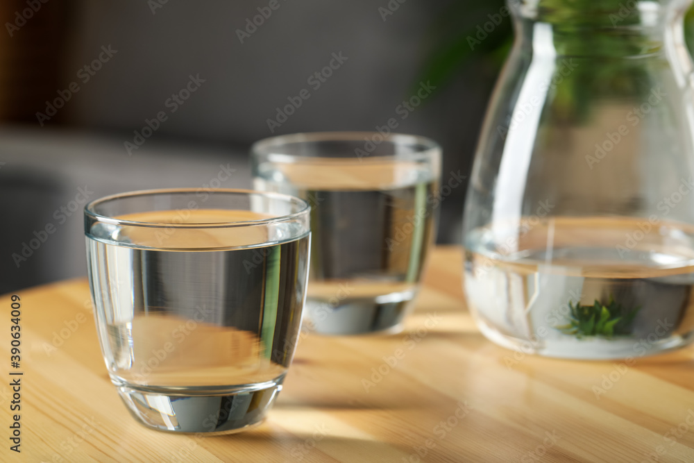 Glass of water on wooden table indoors, space for text. Refreshing drink