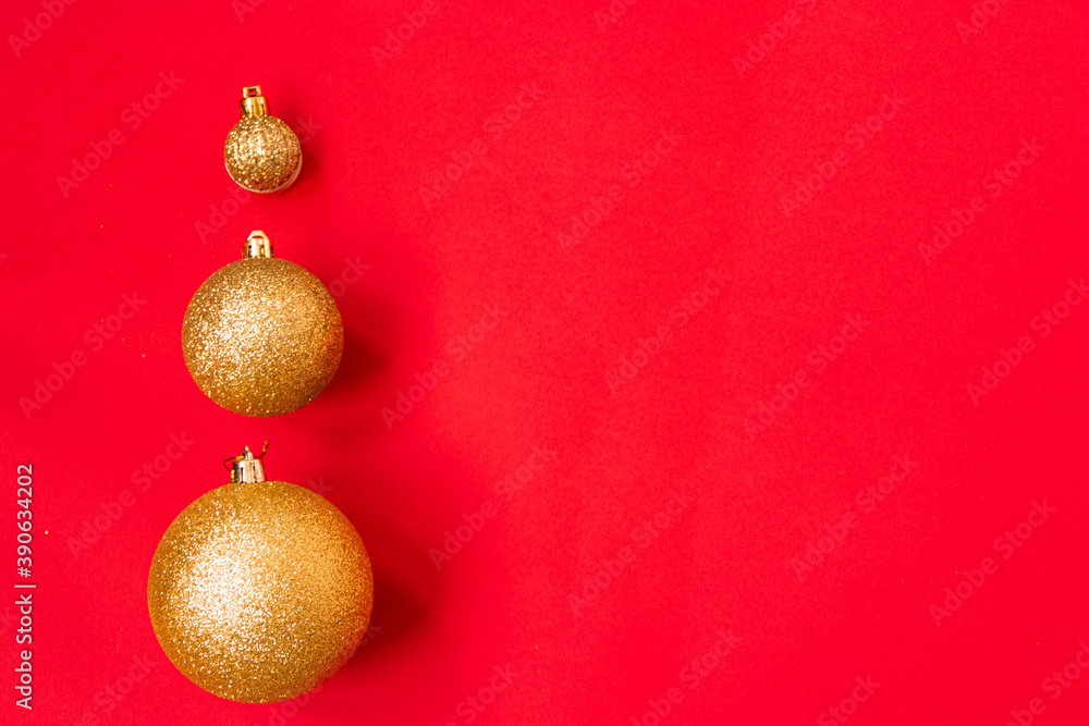 Three golden Christmas balls of different sizes are displayed in a row as a border on a red background. New Year mood mok up. Copy space Three golden Christmas balls of different sizes are displayed in a row as a border on a red background. New Year mood mok up. Copy space