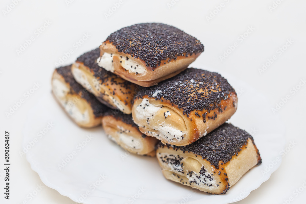 butter cookies with filling and poppy seeds on a white plate on a white background