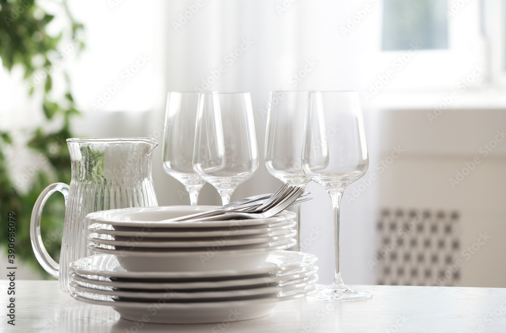 Set of clean dishes, cutlery and glassware on table indoors Set of clean dishes, cutlery and glassware on table indoors
