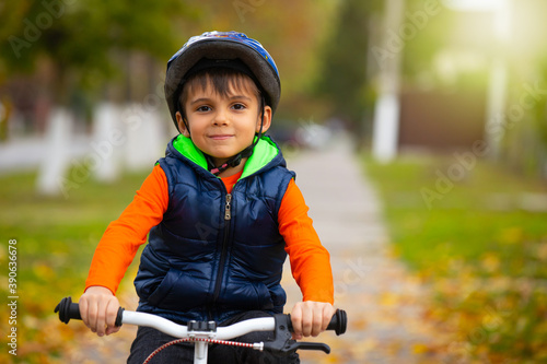  A kindergarten boy wearing a helmet and riding a bicycle on an autumn day. Active healthy outdoor sports. Photo with empty side space