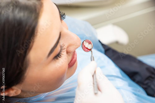 Close-up of young woman having her teeth examinated with mouth mirror