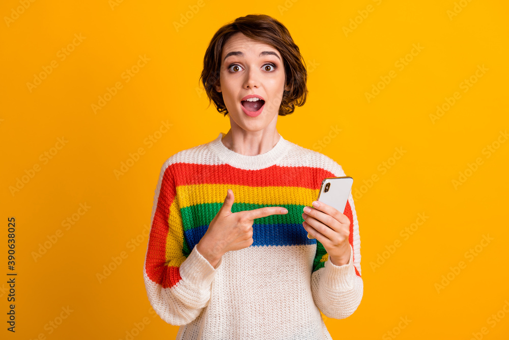 Photo of excited lady hold telephone direct forefinger wear striped pullover isolated yellow color background Photo of excited lady hold telephone direct forefinger wear striped pullover isolated yellow color background