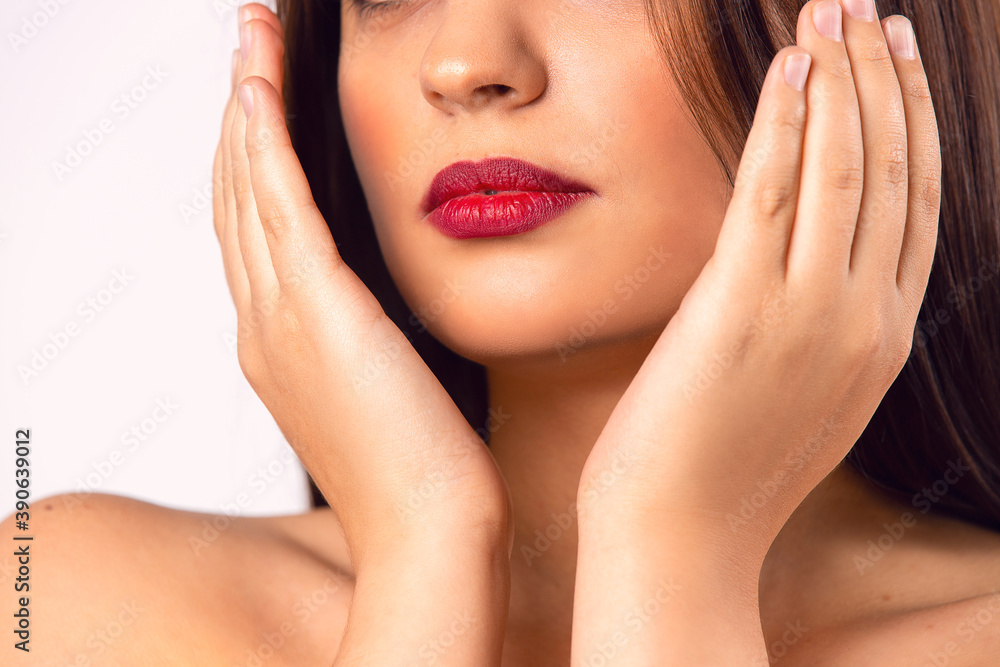 Brunette girl. Beautiful model with red lips. Hands partially covering her face. Beauty and Makeup concept Brunette girl. Beautiful model with red lips. Hands partially covering her face. Beauty and Makeup concept