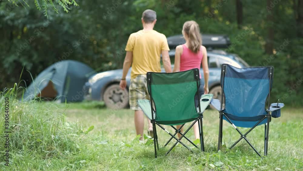 Happy active couple resting at campsite hugging and kissing happily near a car and a tent. Happy active couple resting at campsite hugging and kissing happily near a car and a tent.