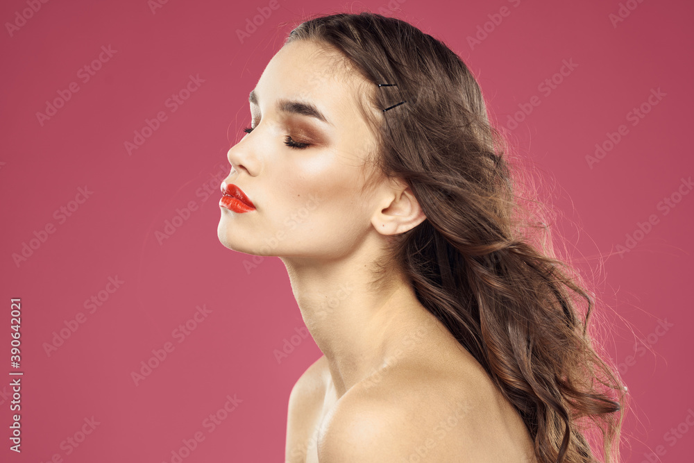 Beautiful brunette woman with makeup on her face on a pink background naked shoulders Beautiful brunette woman with makeup on her face on a pink background naked shoulders