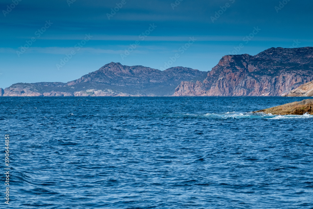 View of the coast of the Freycinet Peninsula, Tasmania from a boat on a sunny day