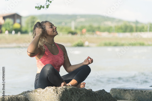 Girl or woman practicing yoga outdoors near a river