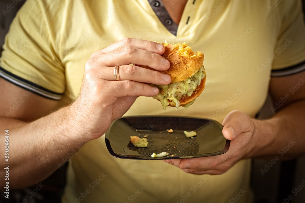 Young hungry man eating a burger . The guy eats fast food, unhealthy food. Diet concept.