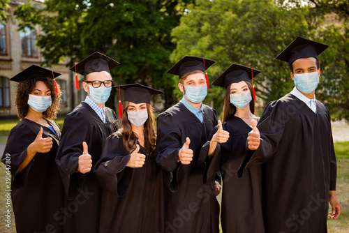 Photo portrait of six graduates showing ok-signs wearing face masks outdoors