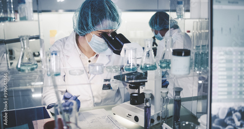 Female science team working on biohazardous samples. Using microscope and computer with data