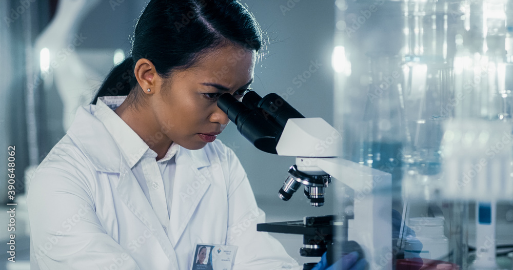 Asian female doctor working late in laboratory. Using microscope Stock ...