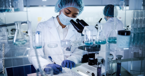 Female science team working on biohazardous samples. Using microscope and computer with data