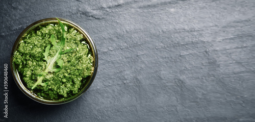 Top view of bowl with arugula pesto on grey table, space for text. Banner design